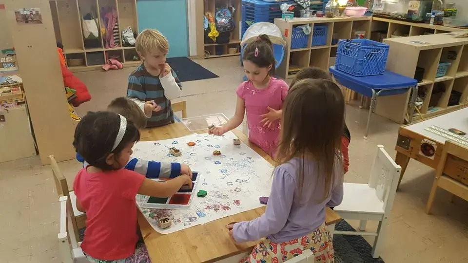 Children exploring art materials together at a classroom table.