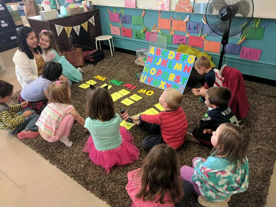 Children gathered with an adult for a classroom group activity.