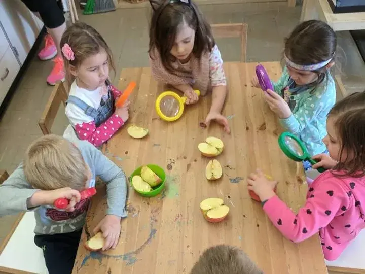 Children exploring food together around a classroom table.