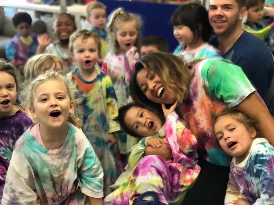 A cheerful group of children and an adult showing their colorful face paint.